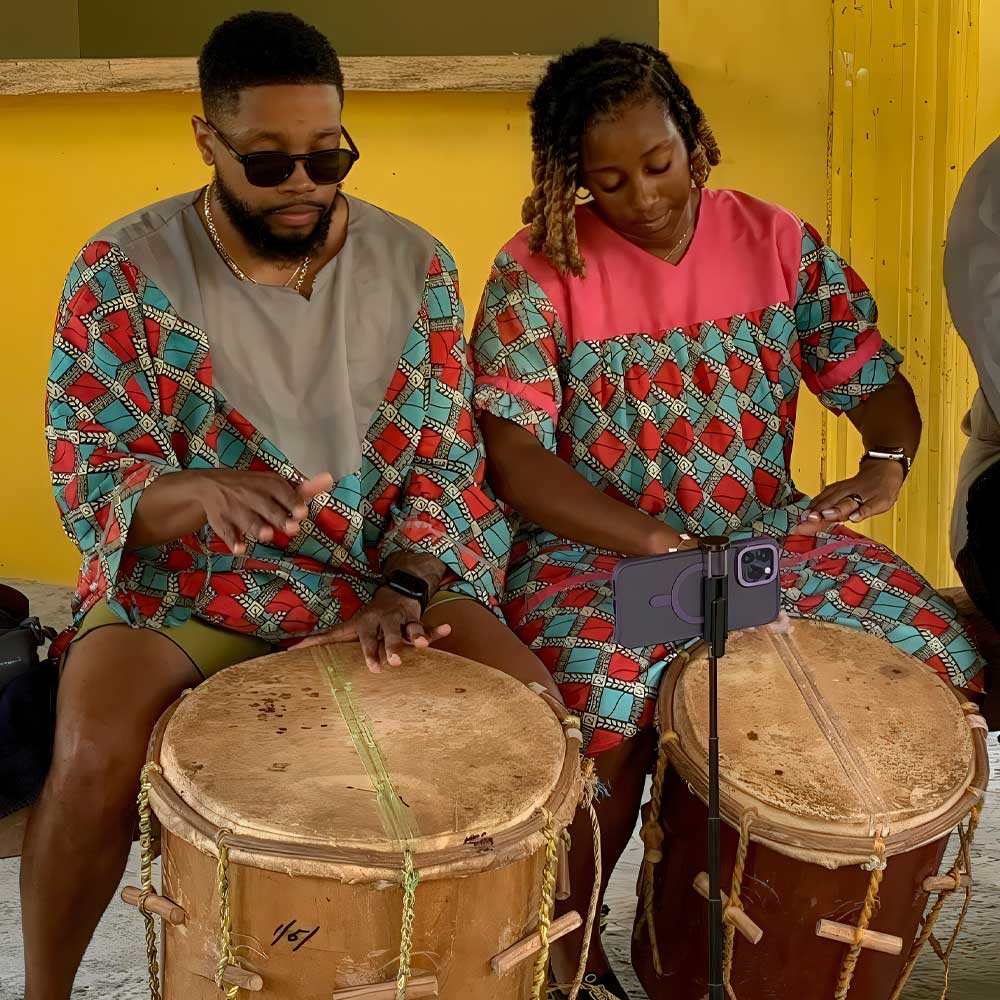 Hopkins-Belize-Travel-Destinations Garifuna man and woman playing traditional drums in Hopkins Village, showcasing vibrant culture and heritage among top Belize travel destinations.
